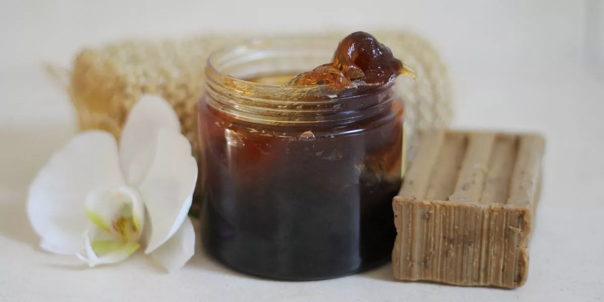 Savon noir à la menthe pouliot : bienfaits, précautions et bonne utilisation 2 Pot de savon noir beldi et pain de savon artisanal posés avec une fleur d'orchidée