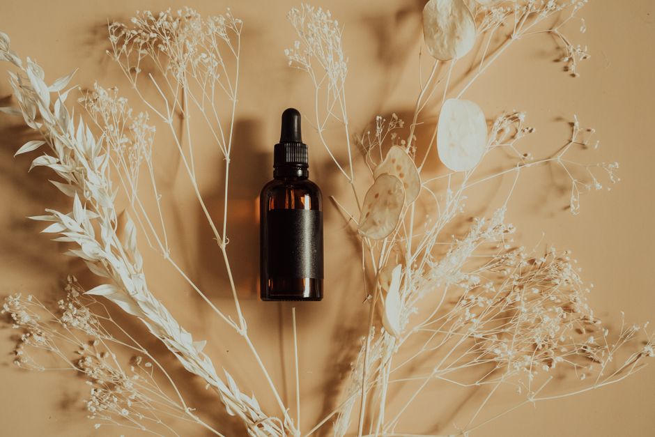 Hydrolat de fleur d'oranger : bienfaits et bonne utilisation pour le visage 3 Flacon ambré entouré de fleurs séchées, hydrolat floral