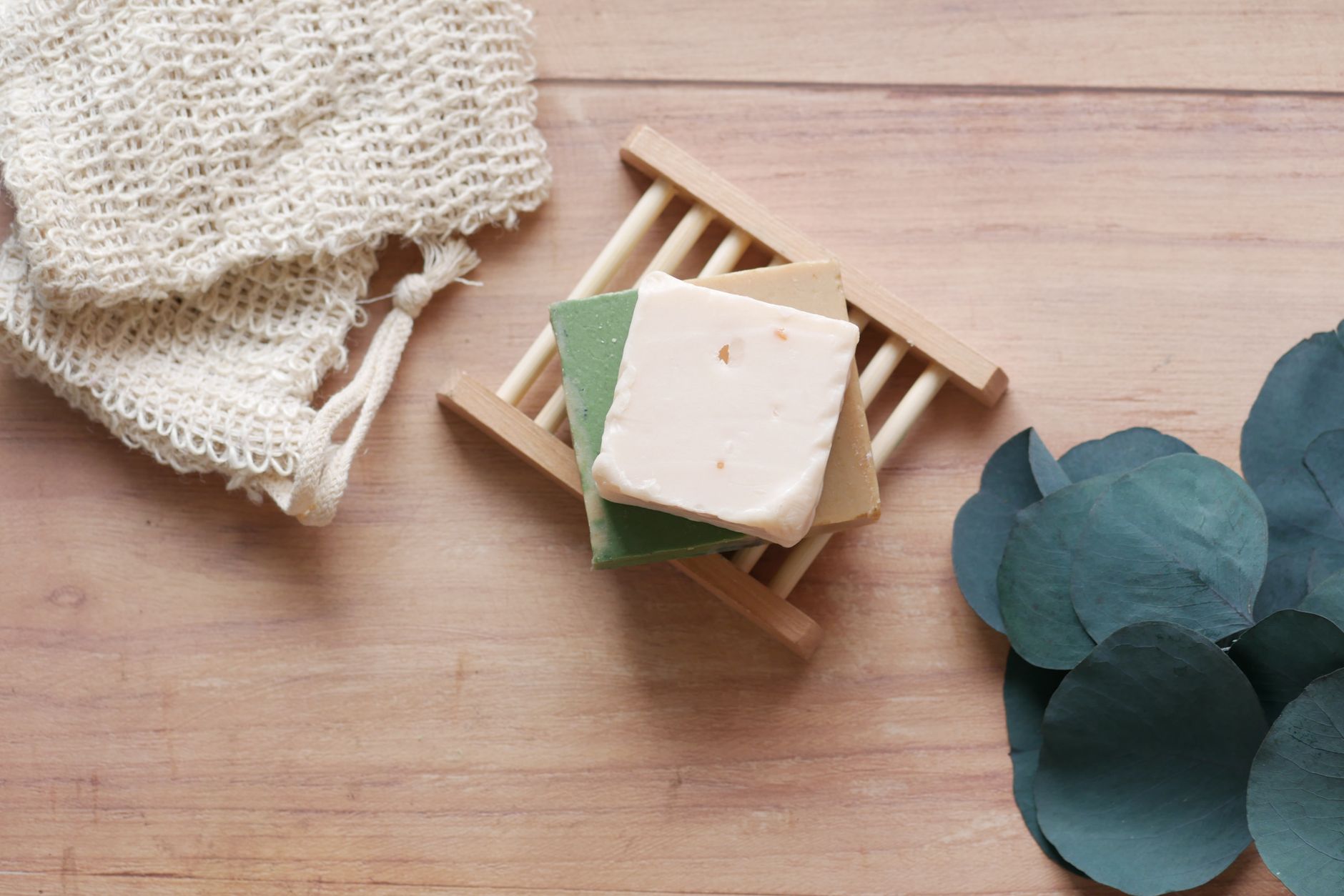 Pains de savon artisanaux aux teintes naturelles, disposés sur un porte-savon en bois